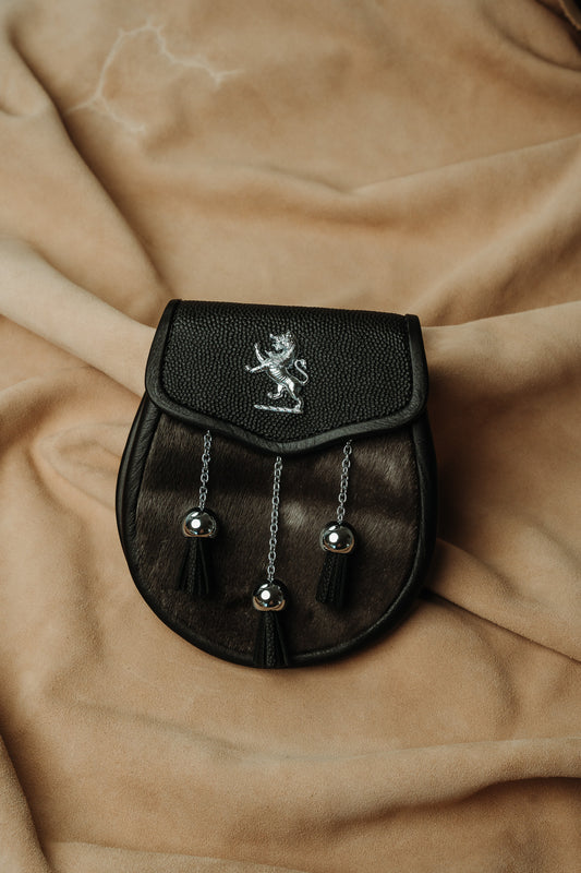 Sporran features luxurious black muskrat fur and a pebbled leather flap with lion badge and surrounding studwork.