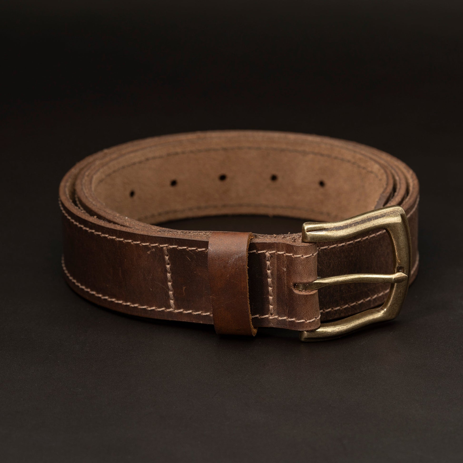 Dark brown leather belt with brass buckle and light stitching