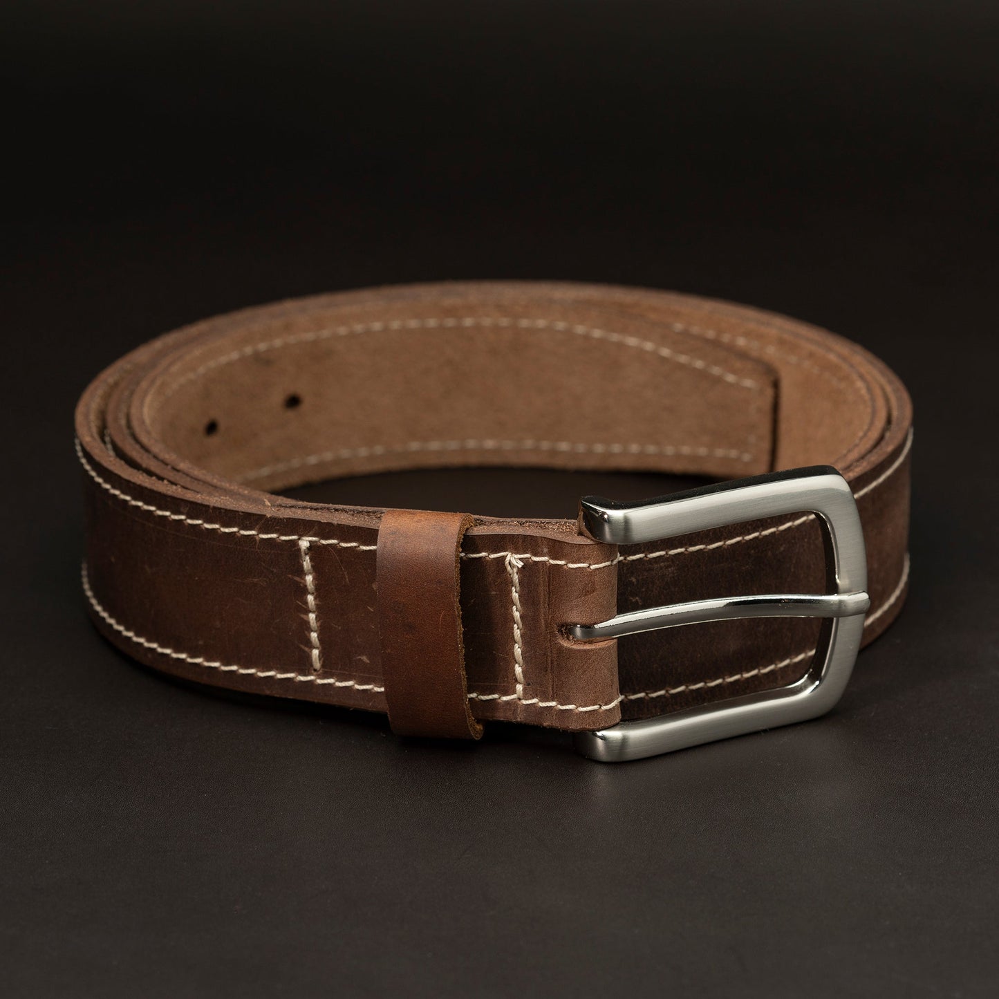 Dark brown leather belt with silver buckle and white stitching
