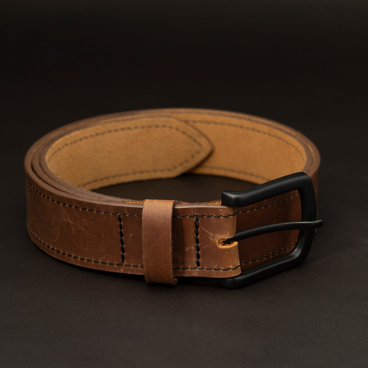 Medium brown leather belt with black buckle and dark stitching
