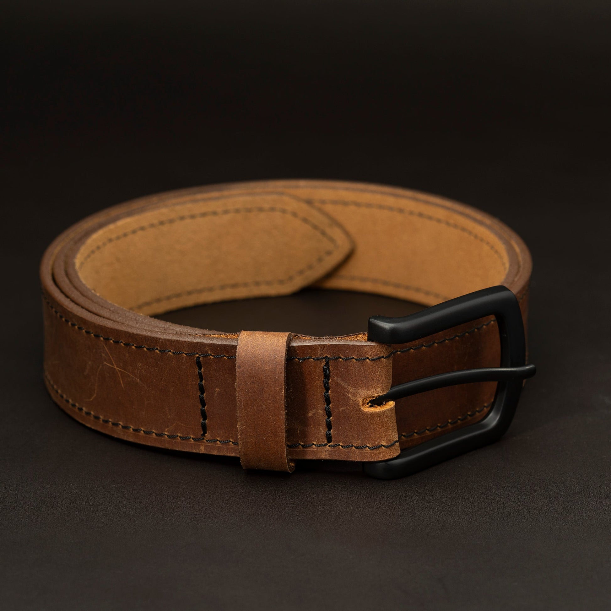 Medium brown leather belt with black buckle and dark stitching