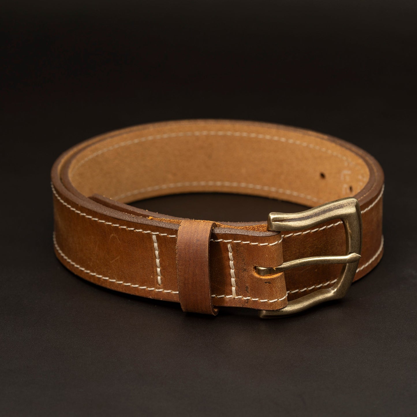 Medium brown leather belt with brass buckle and light stitching