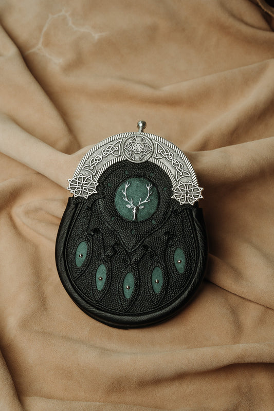This hunting sporran version utilizes pebbled leather petals with green inlay and a targe with a green inlay and a stag badge. It features the standard 5 petals, pewter cantle with celtic knotwork, and chrome studwork.