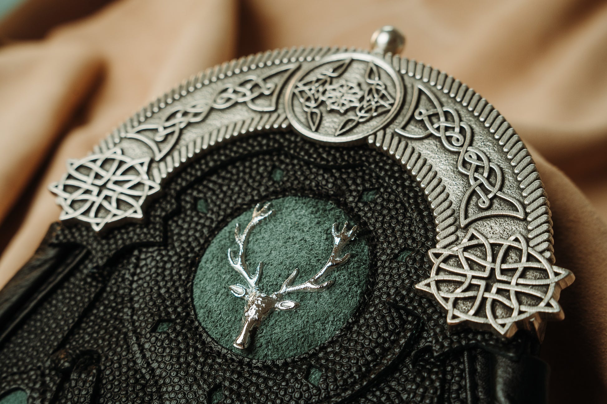 This hunting sporran version utilizes pebbled leather petals with green inlay and a targe with a green inlay and a stag badge. It features the standard 5 petals, pewter cantle with celtic knotwork, and chrome studwork.