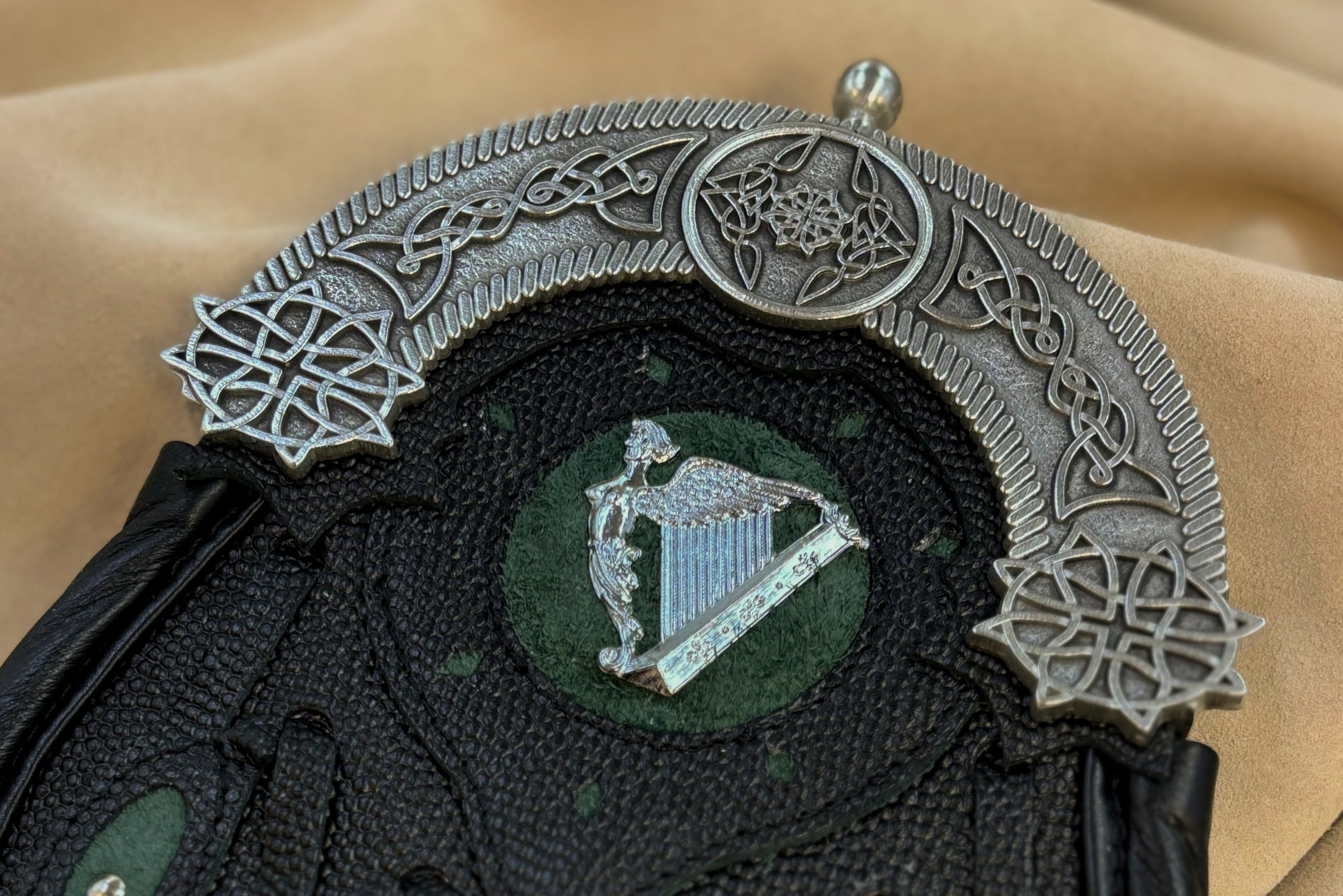 This hunting sporran version utilizes pebbled leather petals with green inlay and a targe with a green inlay and a harp badge. It features the standard 5 petals, pewter cantle with celtic knotwork, and chrome studwork.