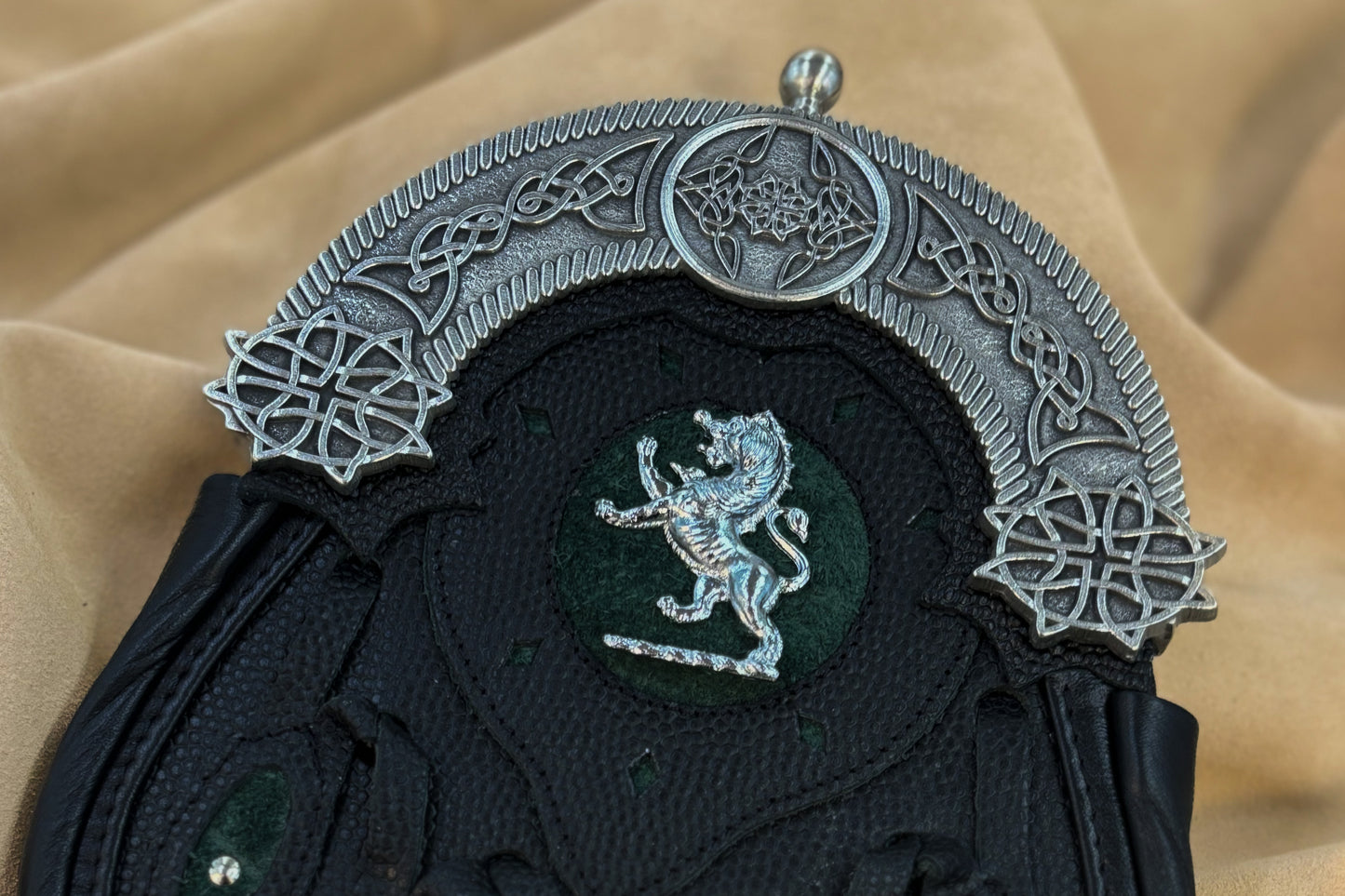 This hunting sporran version utilizes pebbled leather petals with green inlay and a targe with a green inlay and a lion rampant badge. It features the standard 5 petals, pewter cantle with celtic knotwork, and chrome studwork.
