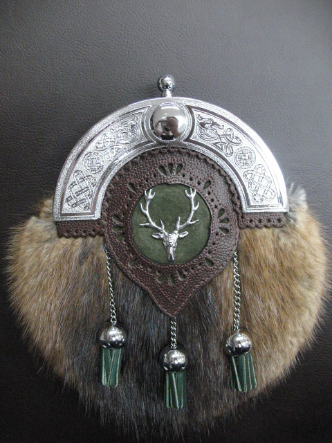 Sporran with brown muskrat fur and forest green suede and pebbled brown leather. The chrome cantle has scrolled dragons and traditional Celtic symbols. The green leather tassels hang on chrome chain and ball bells. The center of the targe a chrome stag is mounted.